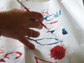 Close-up of hand holding paper with text on table