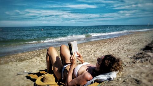 People lying on beach against sky