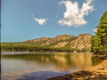 Scenic view of lake by mountains against sky