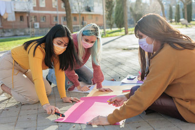 Females wearing mask writing on banners