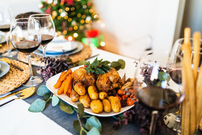 From above of yummy chicken with baked vegetables near glasses of red wine during festive event