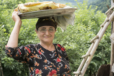 Portrait of smiling senior woman carrying food on head