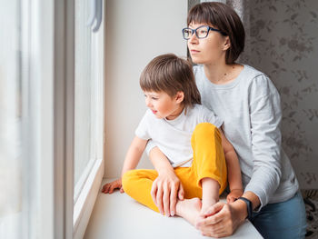 Woman with son looking through window at home