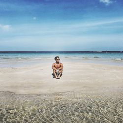 Full length of shirtless man at beach against sky