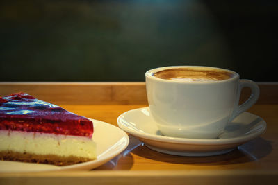 Hot coffee cappuccino latte with cheesecake on wooden background. toned. close-up.