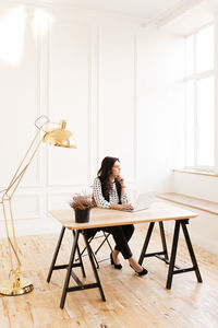 Young woman using laptop while sitting on chair at home