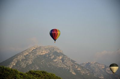 Hot air balloon flying over mountain against sky