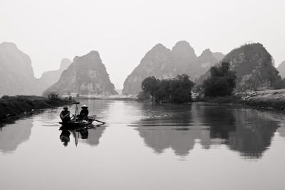 Men traveling in river against rocky mountains