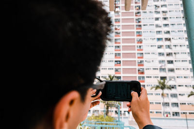 Close-up of man photographing building with mobile phone in city