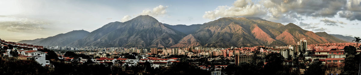 Panoramic shot of town by mountains against sky