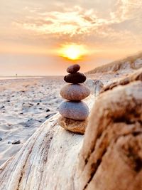 Stack of stones on beach against sky during sunset