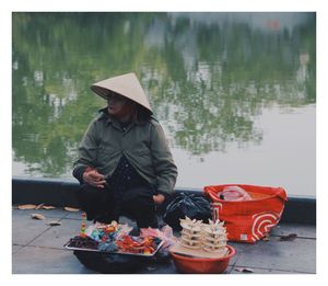 Man wearing hat sitting by lake