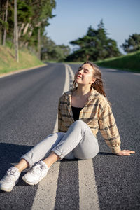 Portrait of young woman sitting on road