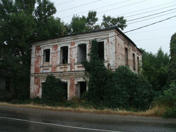Abandoned building by road against trees