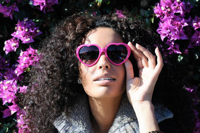 Portrait of young woman wearing sunglasses against bougainvillea
