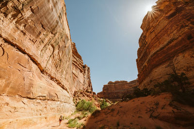 Female hiker looks small at the base of a canyon wall in the maze utah