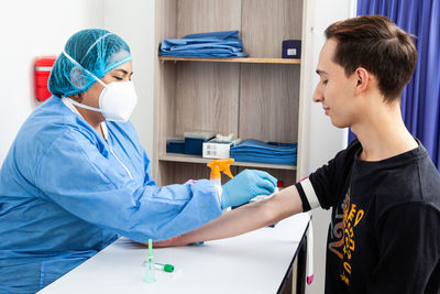 Young female nurse disinfecting a patient's arm before taking a blood sample
