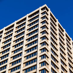 Low angle view of apartment building against clear blue sky