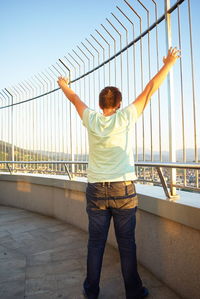 Rear view of man standing on bridge against sky