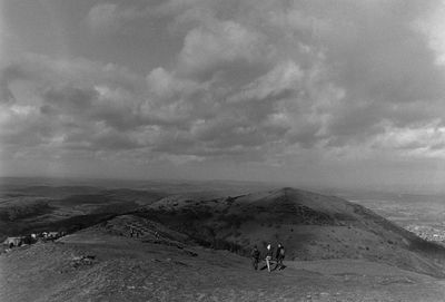 People walking on landscape against sky