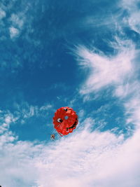 Low angle view of ladybug flying against sky