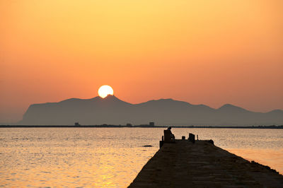 Silhouette pier over lake against sky during sunset