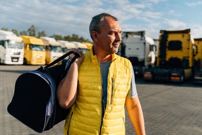 Portrait of caucasian mature man with bag on some-truck vehicles parking