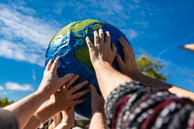 Close-up of hand holding ball against blue sky