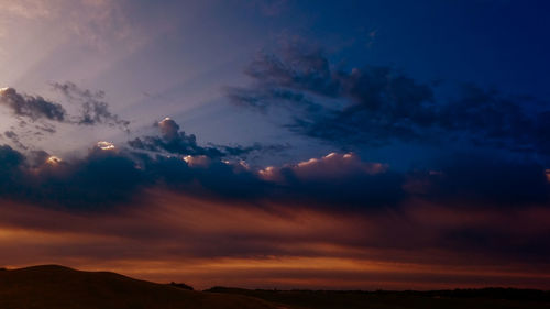 Low angle view of silhouette mountains against dramatic sky