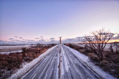 Road amidst snow covered landscape against clear sky