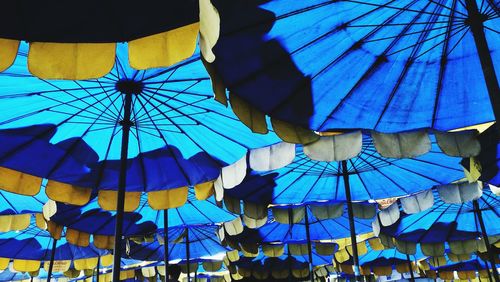 Low angle view of multi colored umbrellas hanging against blue sky