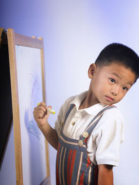 Boy drawing on canvas against wall