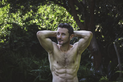 Low angle view of shirtless older man standing against plants