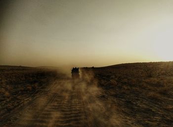 Dirt road amidst land against sky