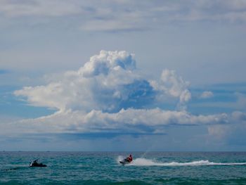 Boat sailing in sea against cloudy sky