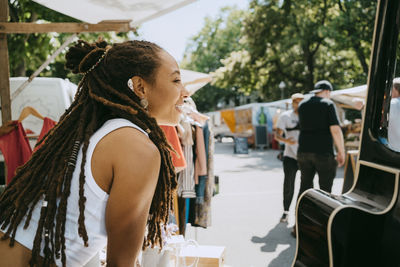 Side view of female owner with dreadlocks in stall at flea market