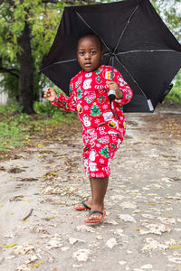 Portrait of cute girl standing in rain during rainy season