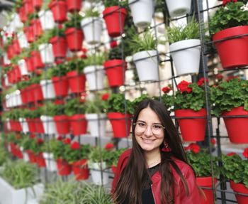 Portrait of smiling young woman against potted plants