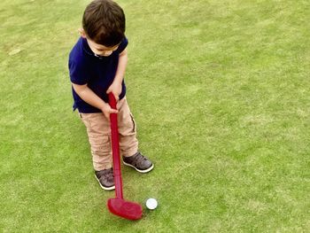 High angle view of boy playing miniature golf on field