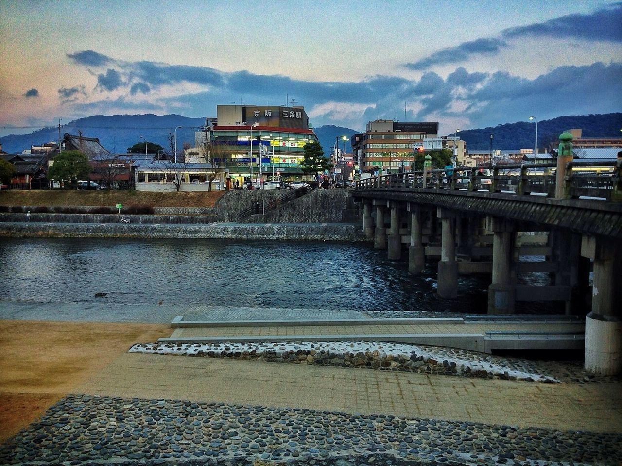 architecture, built structure, building exterior, sky, water, railing, cloud - sky, house, mountain, residential structure, residential building, river, cloud, town, outdoors, day, city, incidental people, roof, no people