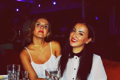 Portrait of female friends smiling while sitting at restaurant