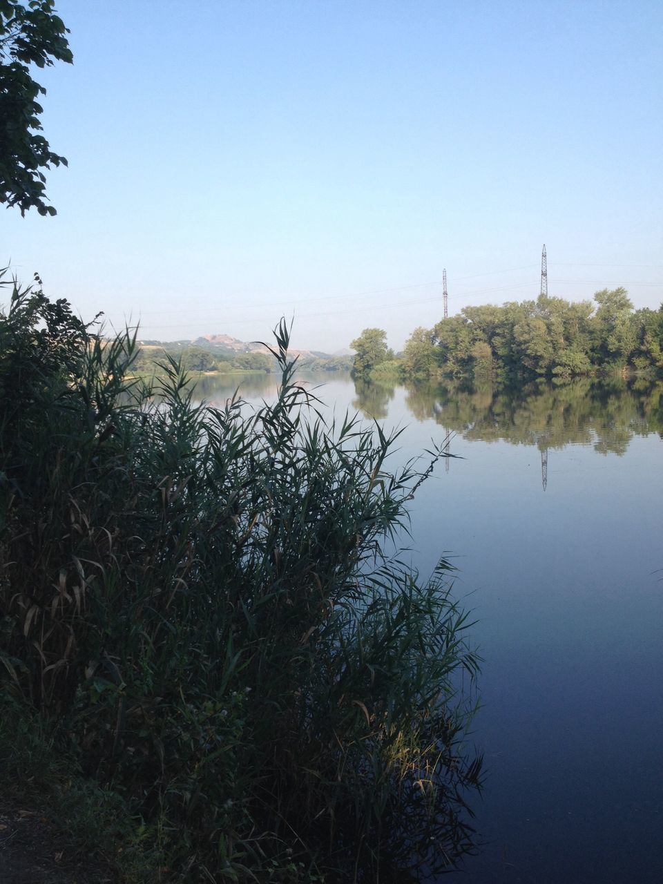 clear sky, water, tranquil scene, tranquility, copy space, lake, tree, scenics, nature, beauty in nature, reflection, growth, plant, blue, river, waterfront, mountain, day, idyllic, calm