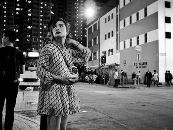 Young woman standing in illuminated city at night
