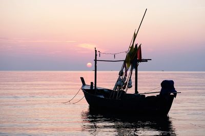 Fishing boat in sea against sky during sunset