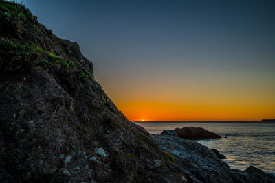 Close-up of rock by sea against sky during sunset