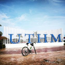 Bicycle parked by railing against sky