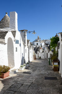 Alley amidst buildings in city against clear blue sky