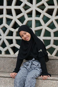 A happy face of an asian girl sitting nearby the lake at the landmark of putrajaya malaysia