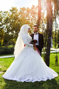 Bride and bridegroom standing at park