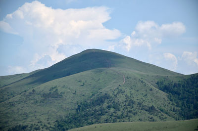 Mountain with a path beneath blue sky